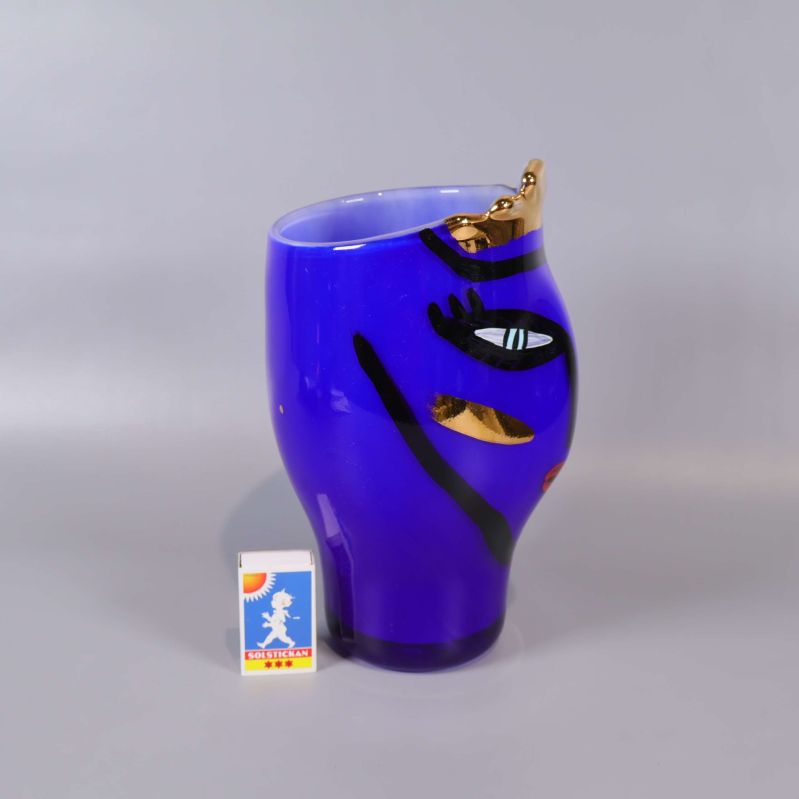 Sidosikt av vas med ansiktsmotiv, tändsticksask bredvid