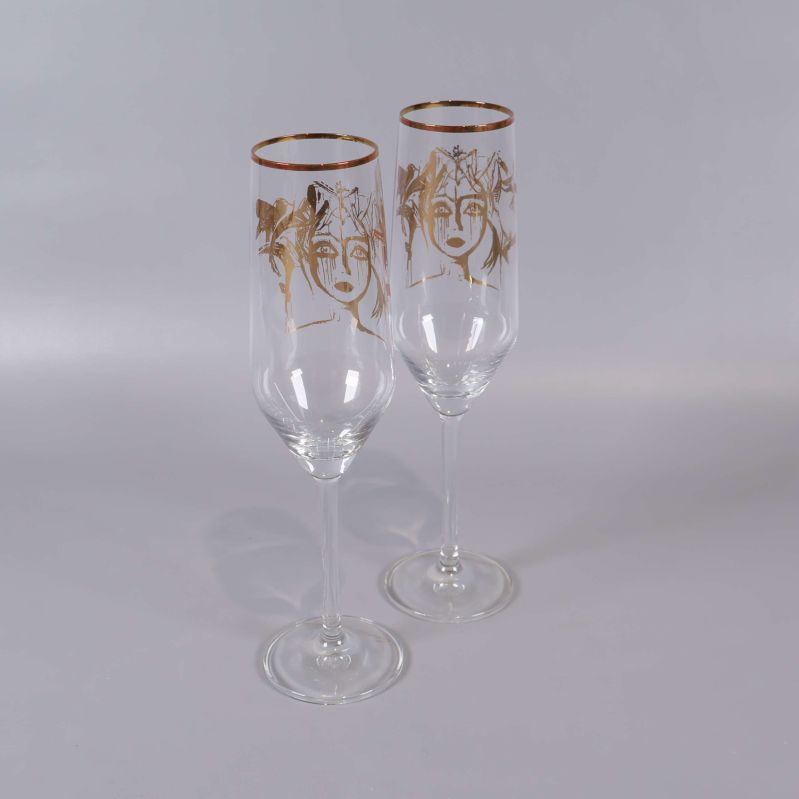 Två champagneglas med guldmotiv och guldkant sedd snett från sidan