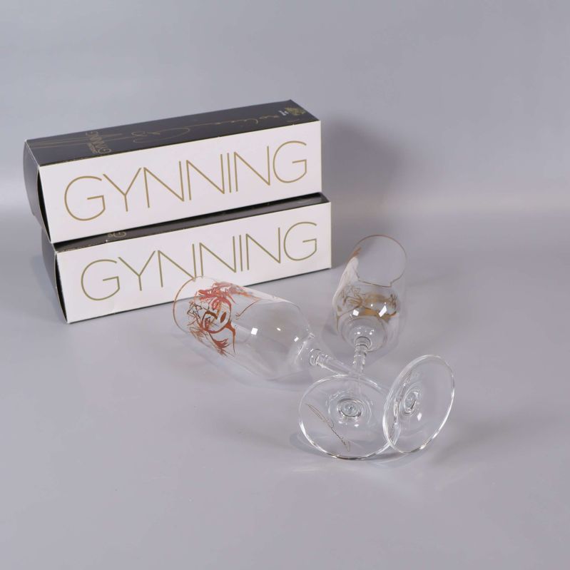 Två liggande champagneglas och två askar med Gynning-tryck