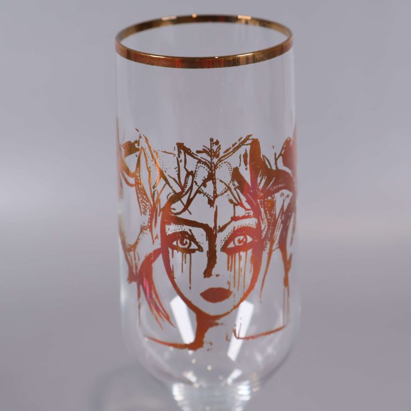 Närbild på glasets ansiktsmotiv i guld
