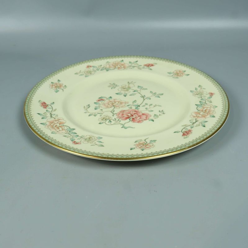 Låg tallrik med blommönster och guldkant från sidan