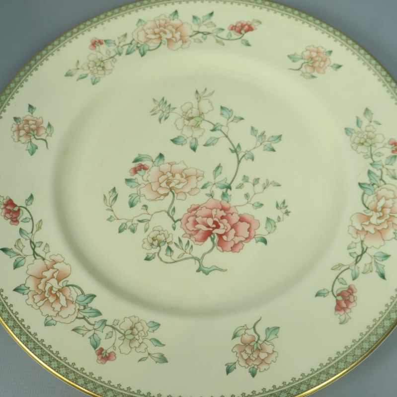 Närbild av blommigt mönster på tallrik med guldkant