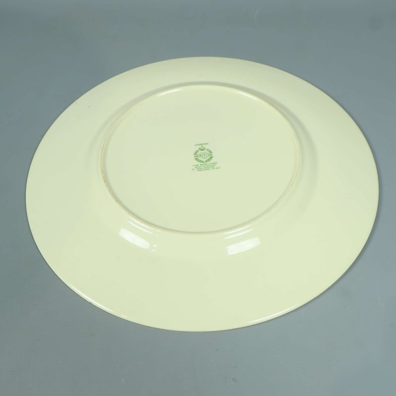 Baksidan av tallrik i gräddvitt med grön stämpel