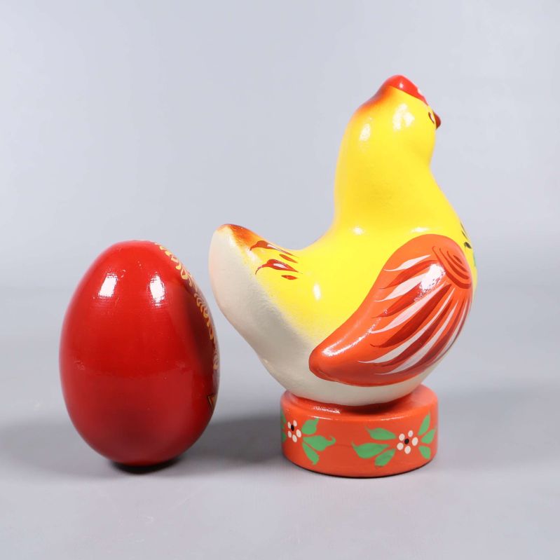 Bakifrån på gul träfigur höna och rött ägg