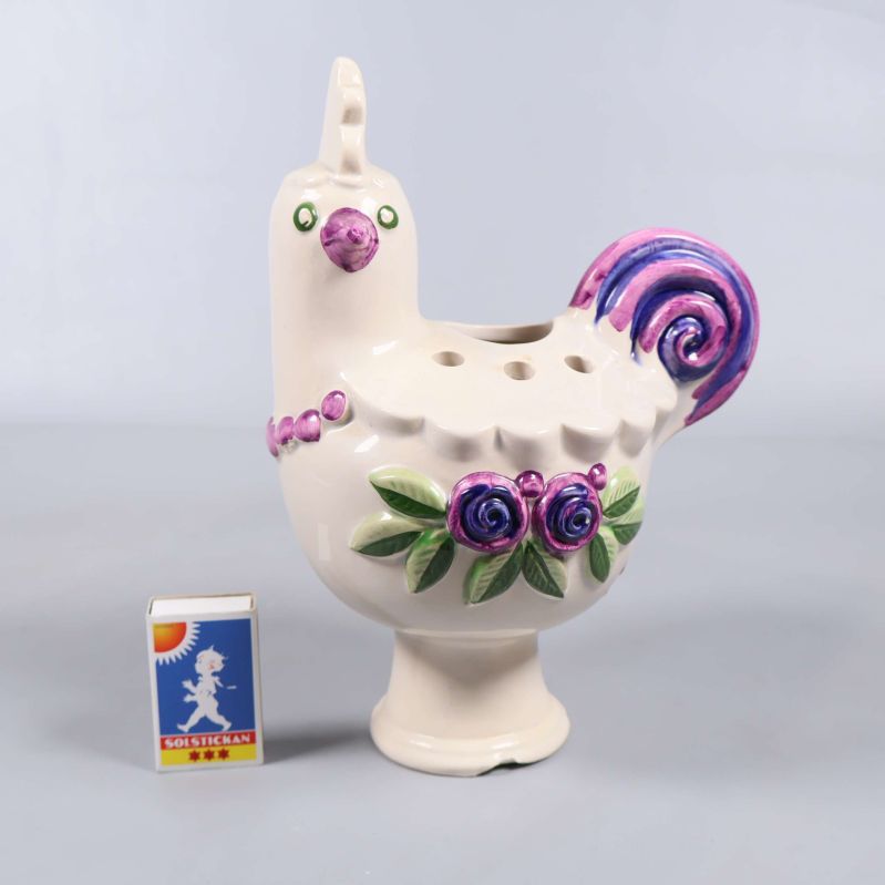 Keramisk kyckling visas bredvid ett tändsticksask för storleksreferens