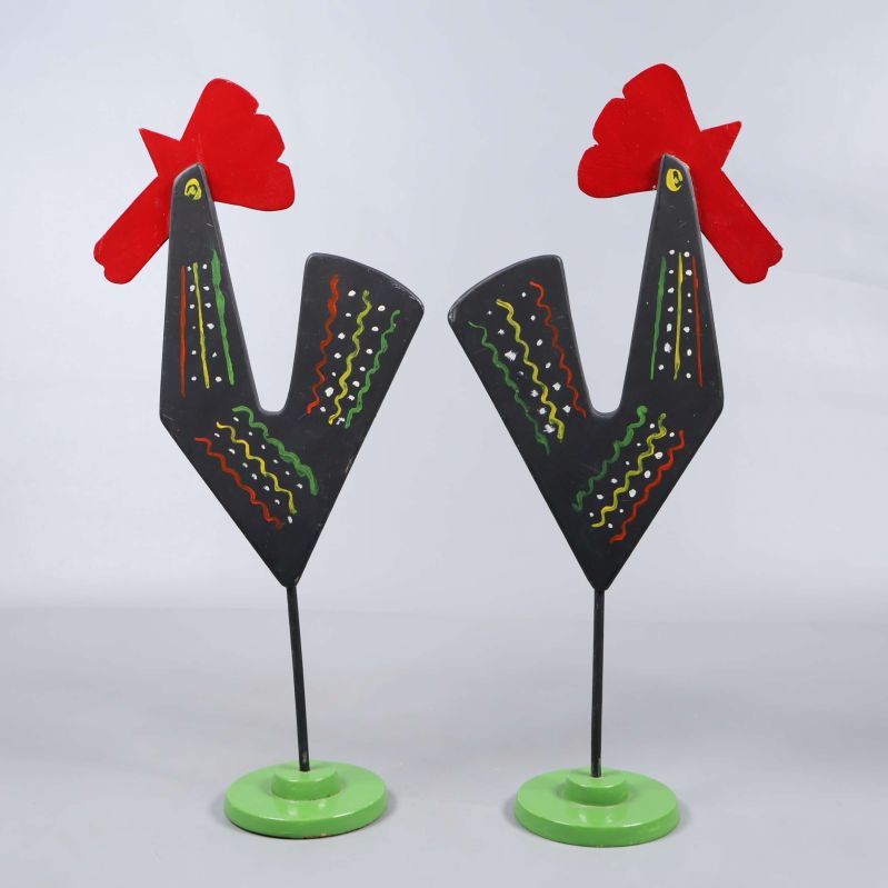 Två målade tuppar med svarta kroppar och gröna baser mot ljus bakgrund