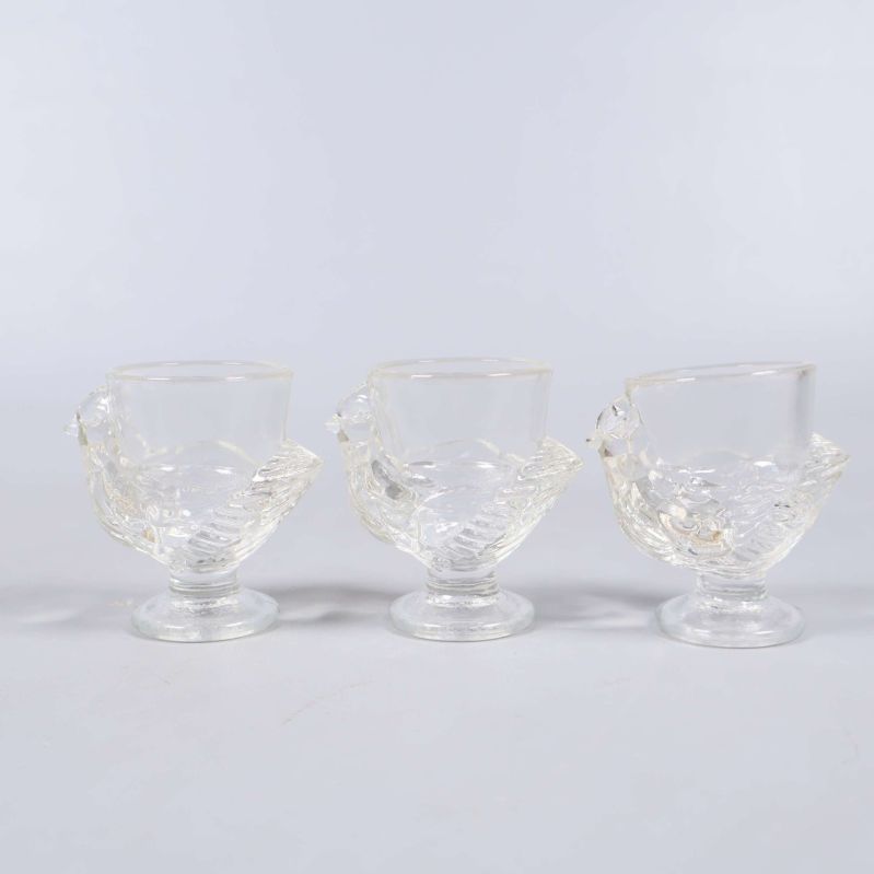 Tre små fågelglas stående i rad mot ljus bakgrund