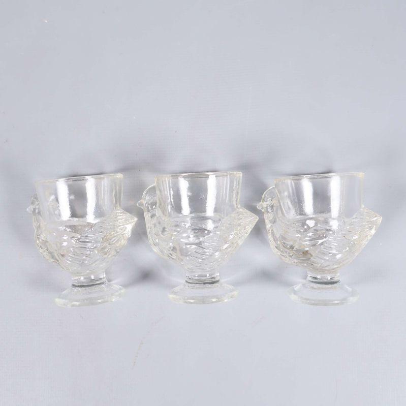 Tre små klara glas i rad mot neutralt underlag