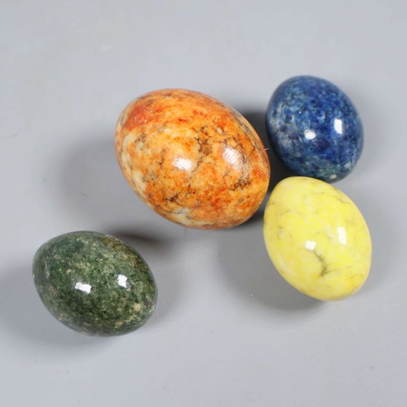 Fyra dekorativa ägg i färgad sten på grå bakgrund