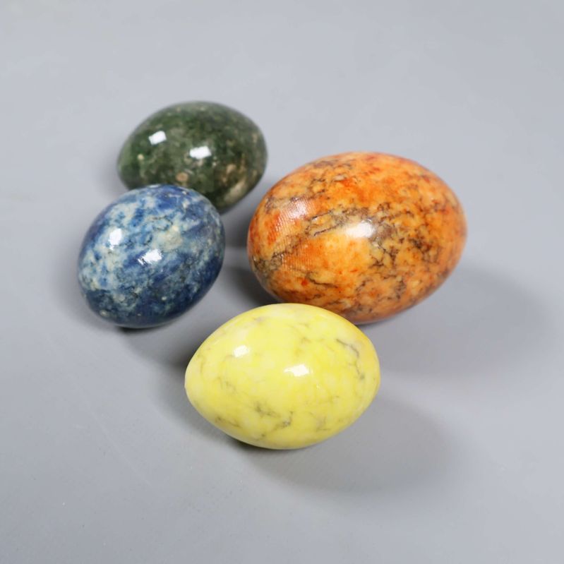 Dekorativa färgade stenägg samlade på grå bakgrund