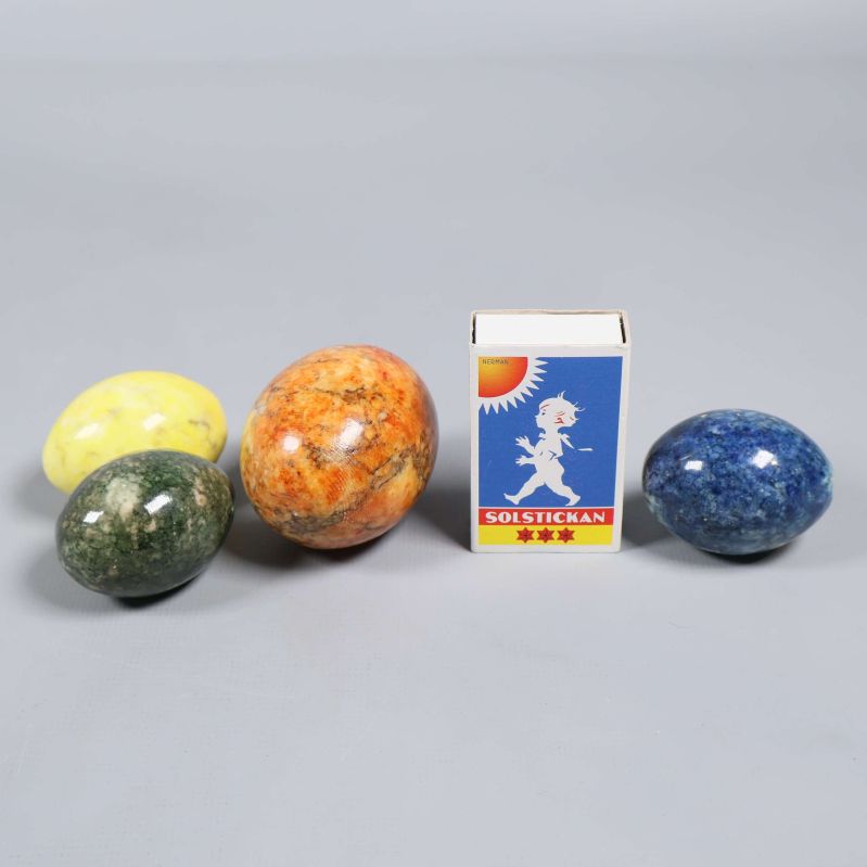 Stenägg i olika färger jämte en tändsticksask