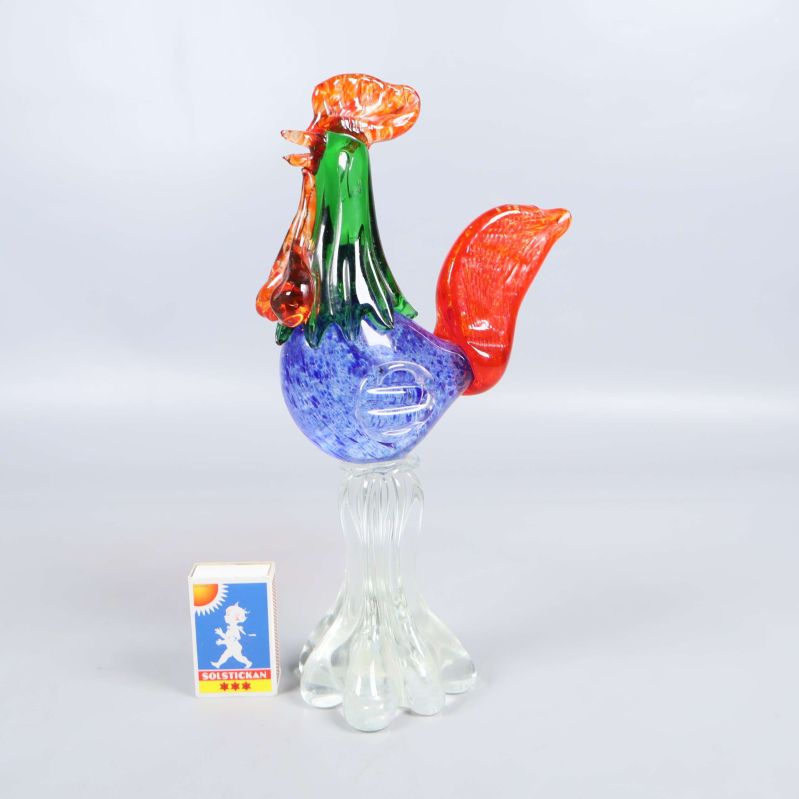 Färgglad glasfigur föreställande tupp med tändsticksask jämte