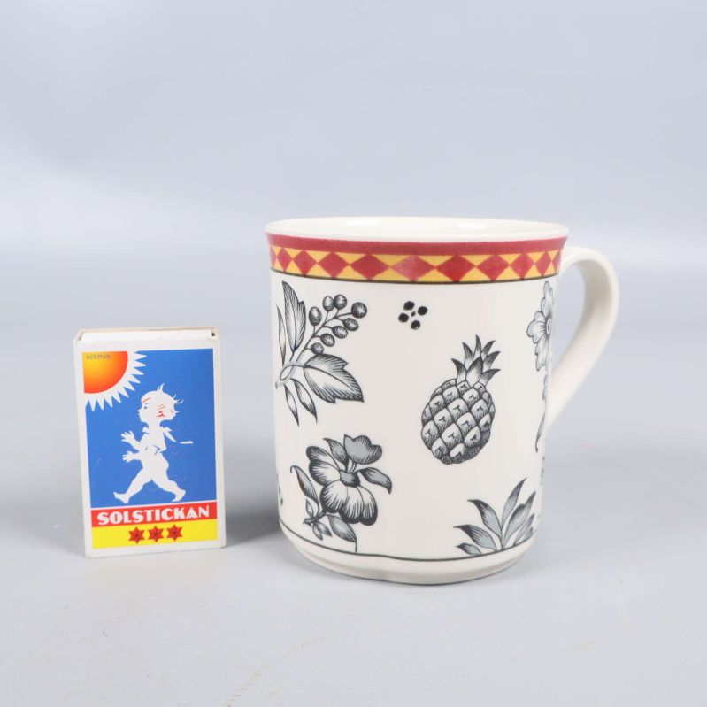 Mugg med blomdekor bredvid tändsticksask