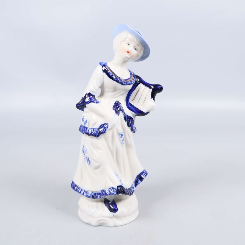 Porslinsfigur i blått och vitt med harpa och hatt