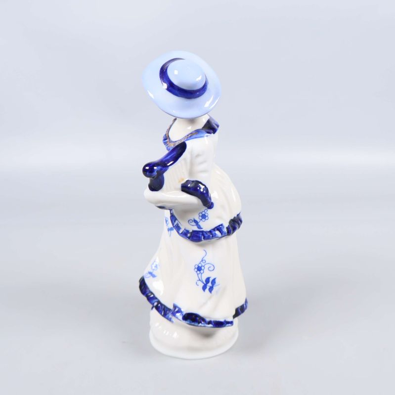 Porslinsfigur bakifrån visar blå hatt och klänning