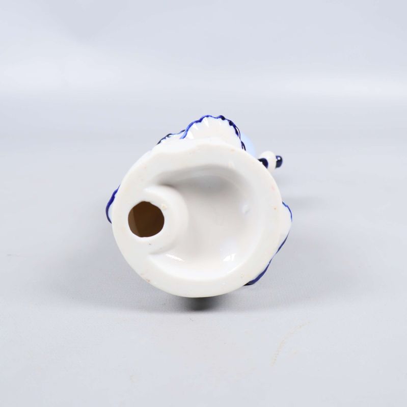 Undersida på porslinsfigur visas mot ljus bakgrund