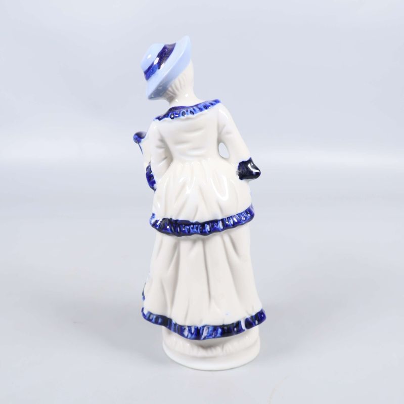 Porslinsfigur bakifrån visar klänning och hatt i blått