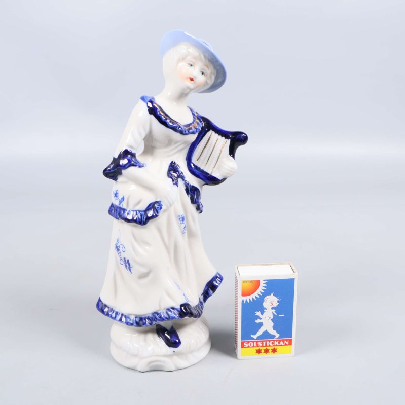 Porslinsfigur bredvid tändsticksask för storleksreferens