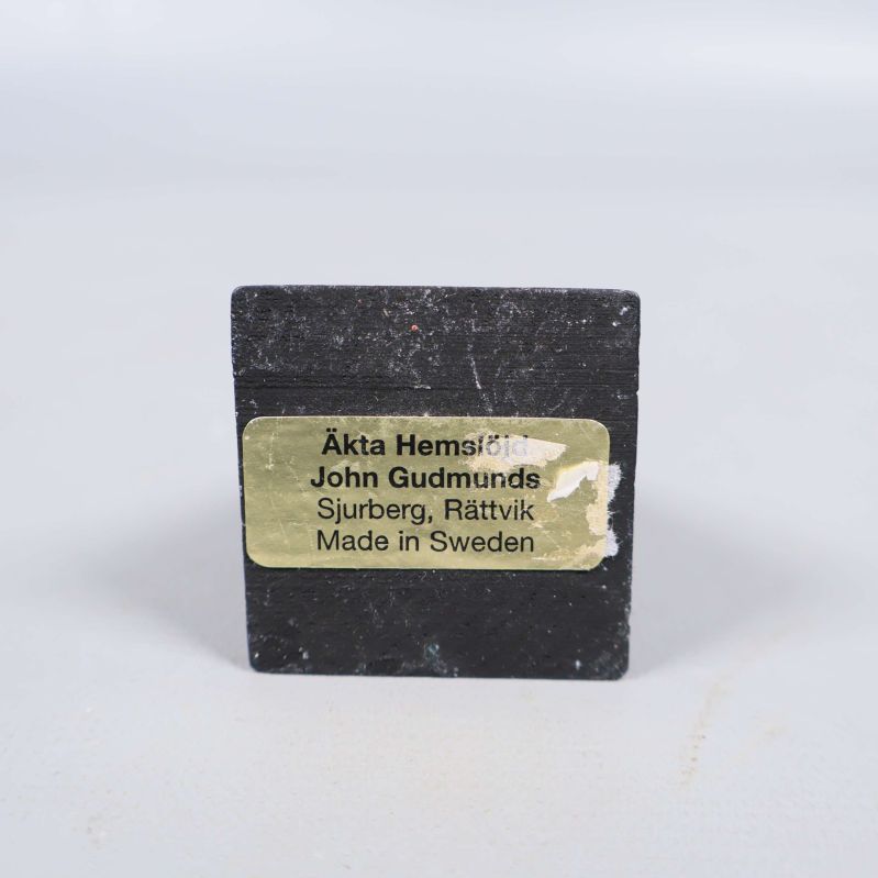 Gul etikett med text från John Gudmunds på tuppfot