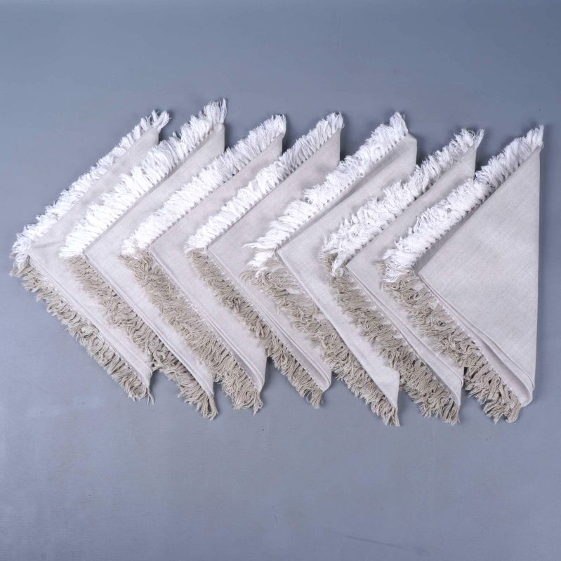 Åtta beige servetter med fransar upplagda i rad