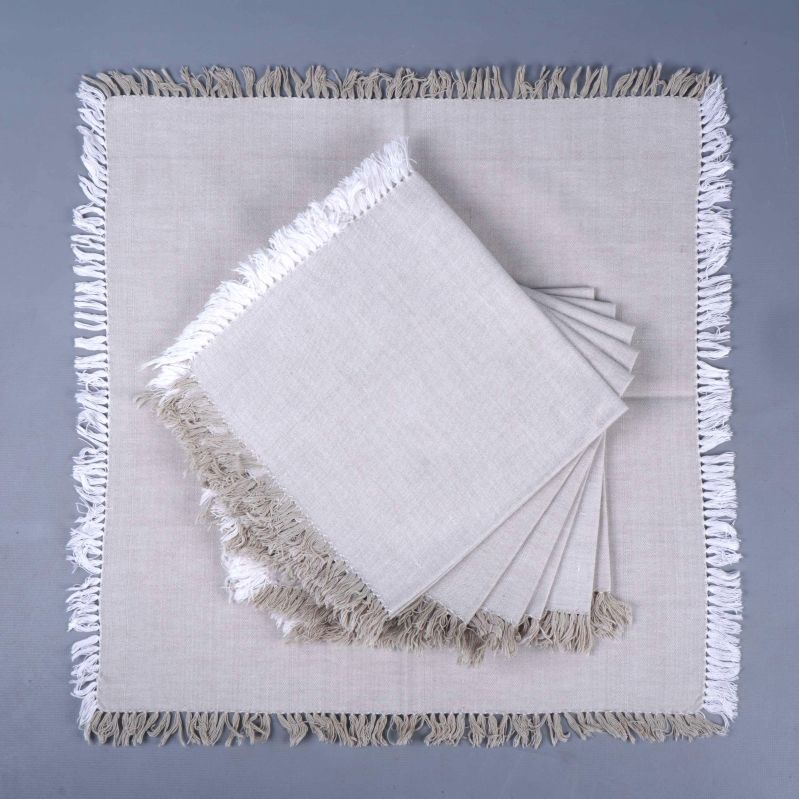 Beige servett utslagen med flera vikta servetter ovanpå