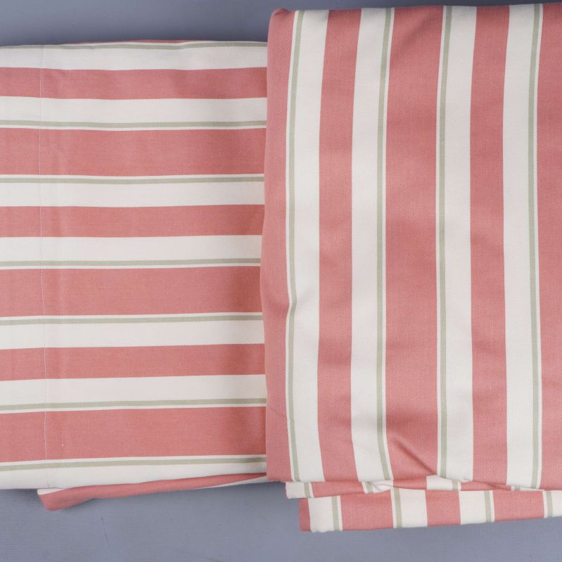 Uppvikta och vikta gardinlängder i rosa och vitt med smal grön rand