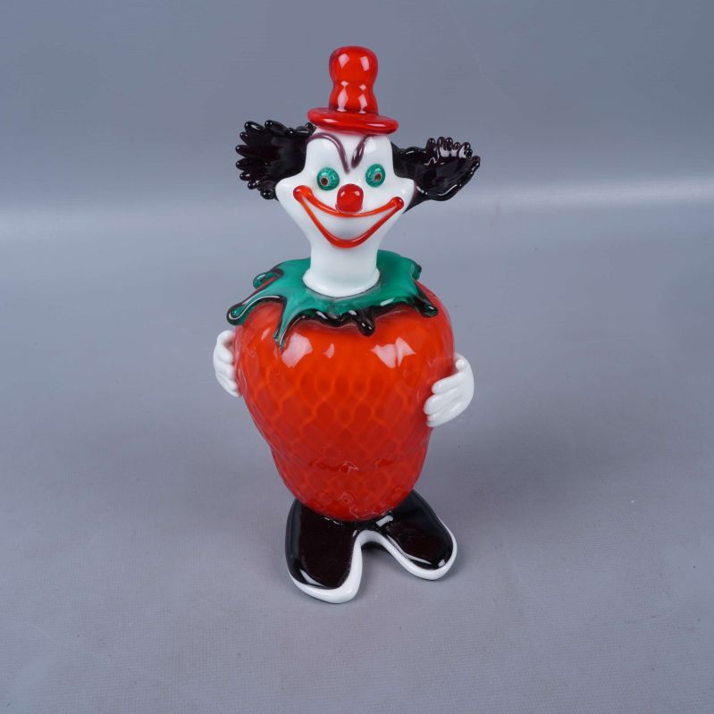 Clownfigur håller en röd jordgubbe med svarta skor