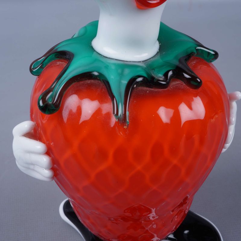 Närbild av jordgubbens yta och gröna blad på clownfiguren