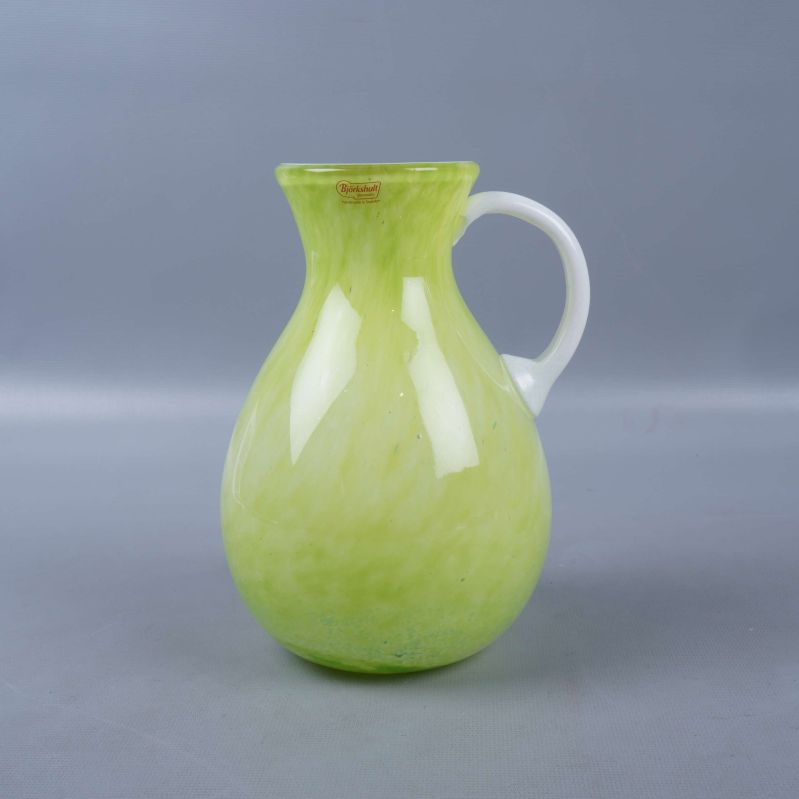 Grön vas med vitt handtag fotograferad framifrån