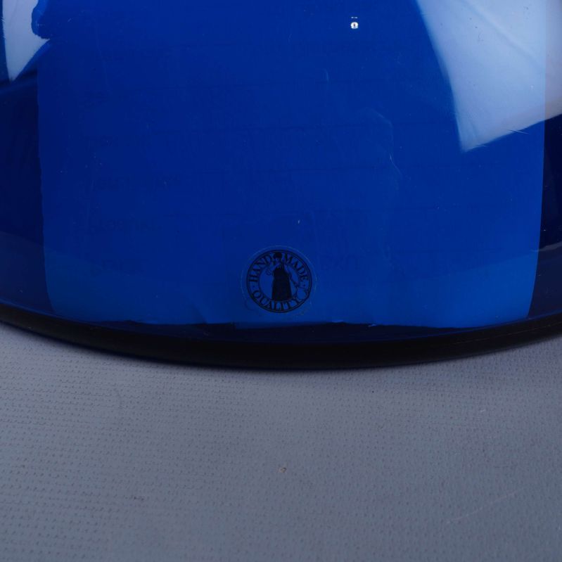 Närbild av tryckt logotyp under blå glasvas