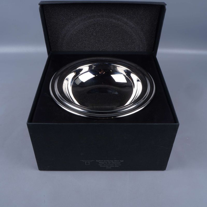 Blank metallskål placerad i svart presentask