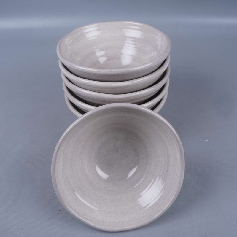 Sex ljusgrå skålar staplade och en vänd mot kameran