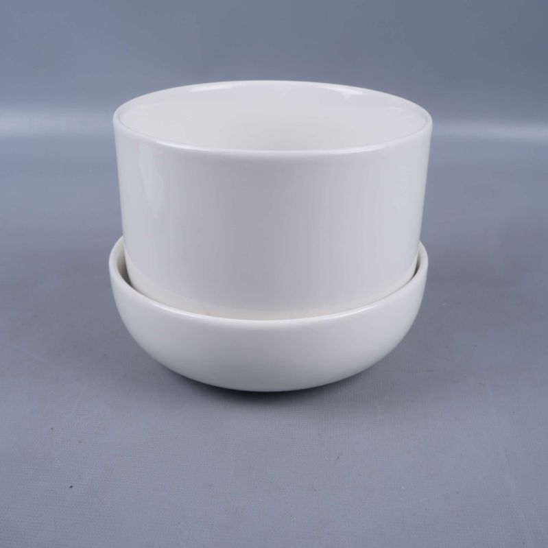 Vit rund kruka med fat mot grå bakgrund