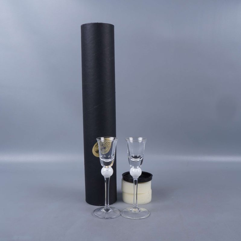 Två snapsglas med vit kula och svart förvaringsetui