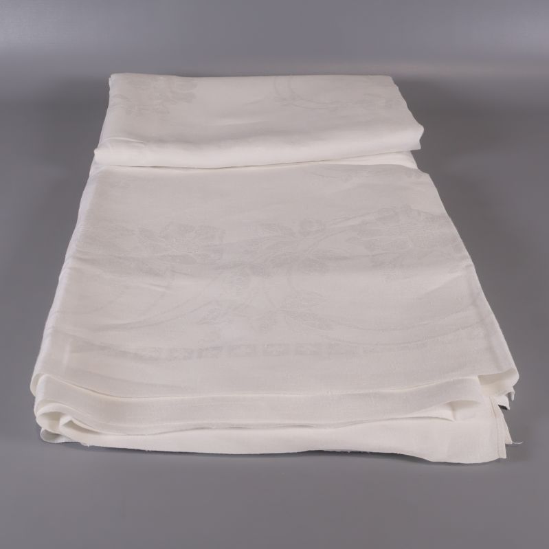 Uppvikt vit duk med synligt blomdetaljmönster