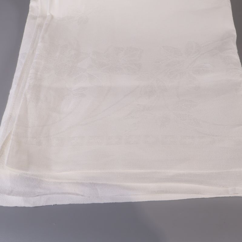 Närbild på dukens hörn och diskret vävt blommotiv