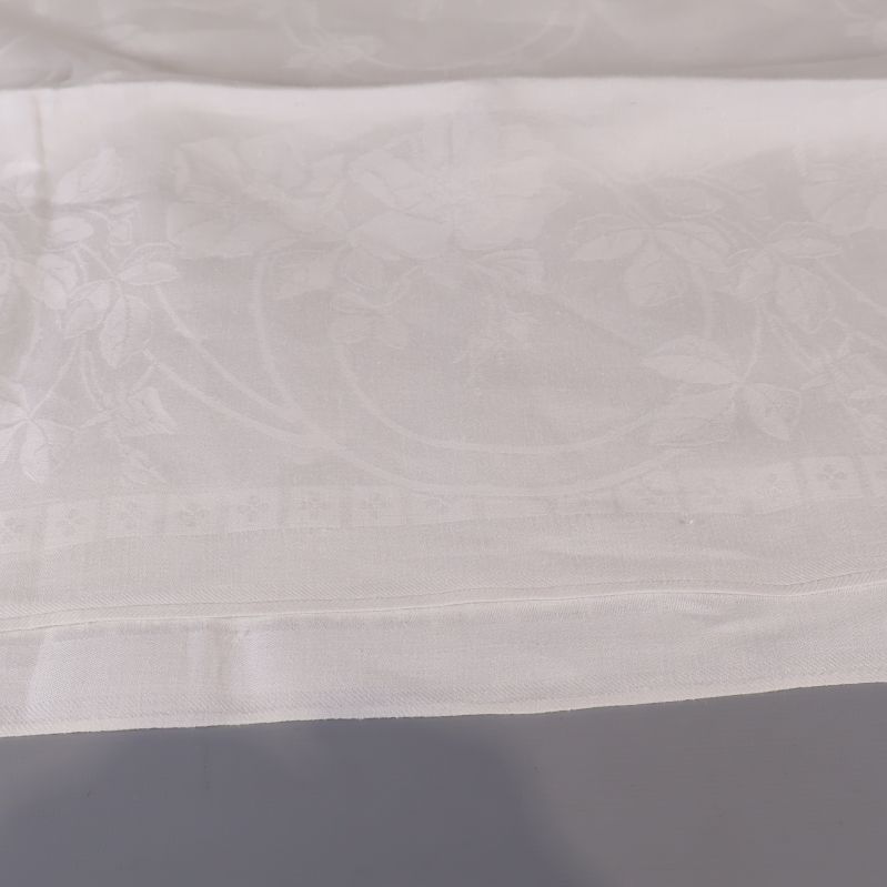 Kant av vit duk med blommotiv och dekorativ ram