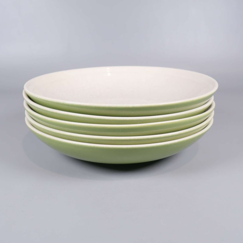 Staplade tallrikar visar grön utsida och vit insida