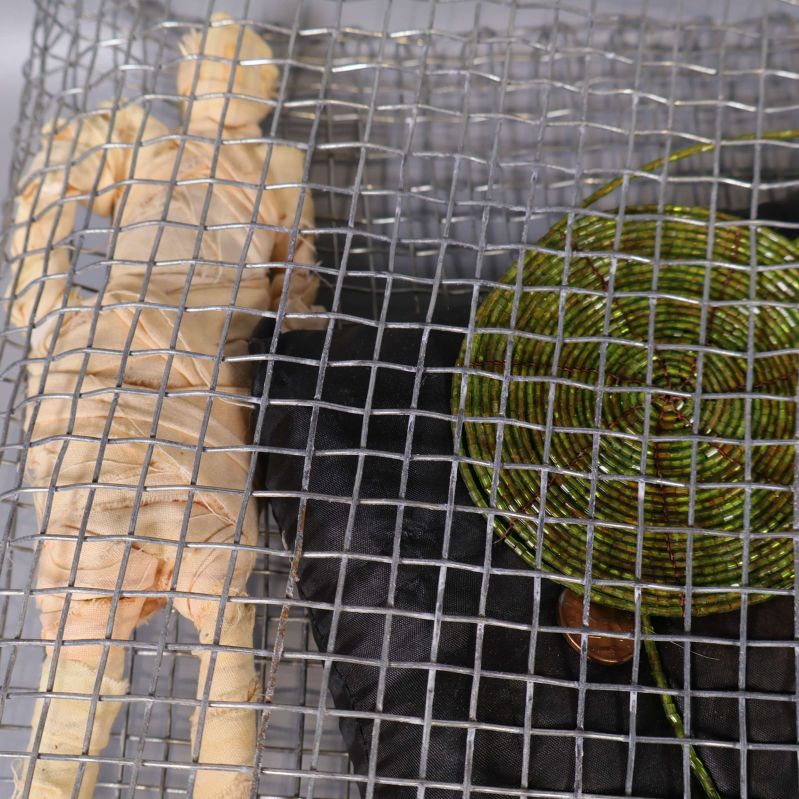 Närbild på figurdocka och grönt cirkulärt objekt i nätet