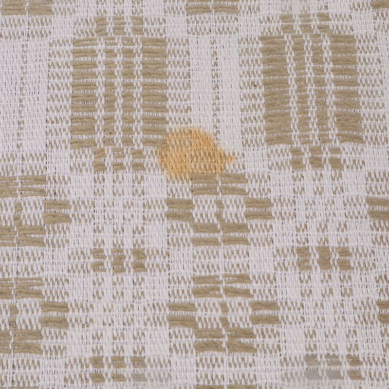 Närbild på fläck på vävd beigevit duk