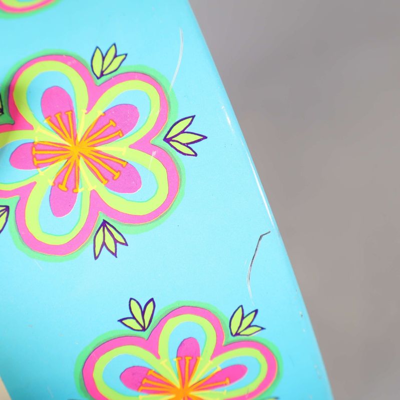 Närbild på turkos blommönster och repor i ytan