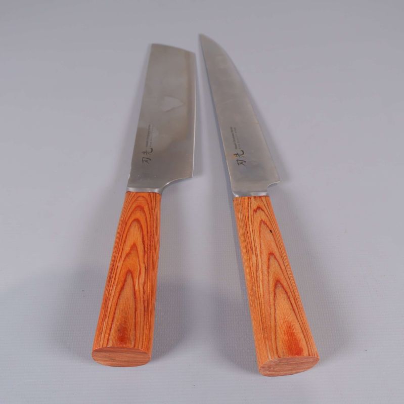 Två köksknivar uppackade med blad och träfärgade handtag