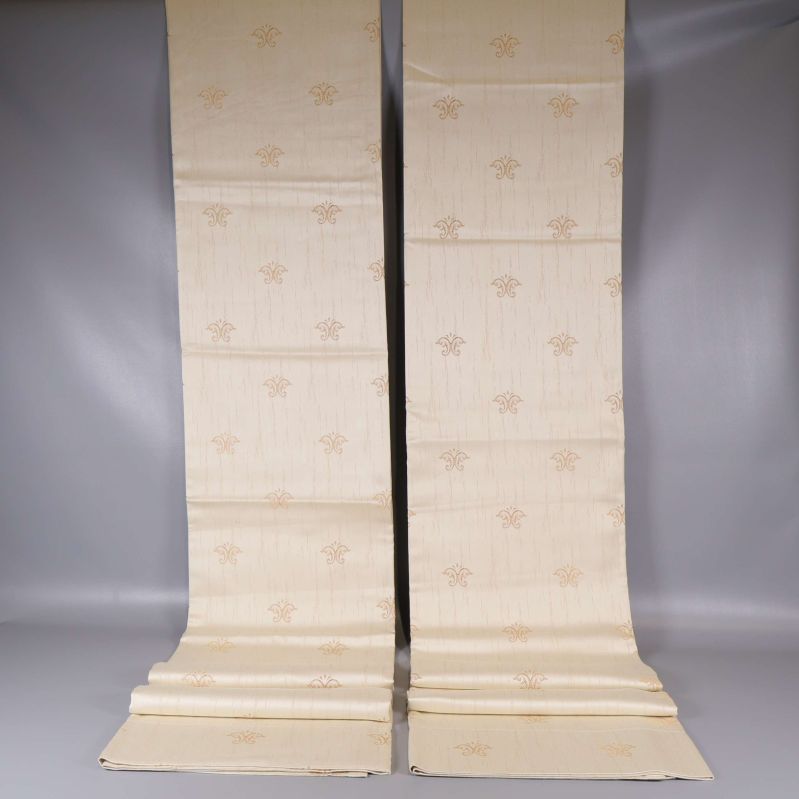 Två upprullade ljusa gardinlängder mot grå bakgrund