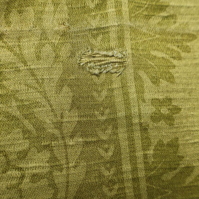 Närbild av mindre skada på draperiets textil