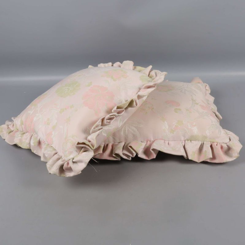 Två kuddar med volangkant ligger snett mot varandra