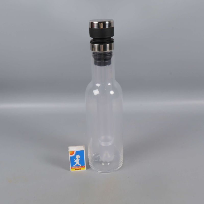 Karaff i glas med metallock intill tändsticksask för storleksjämförelse