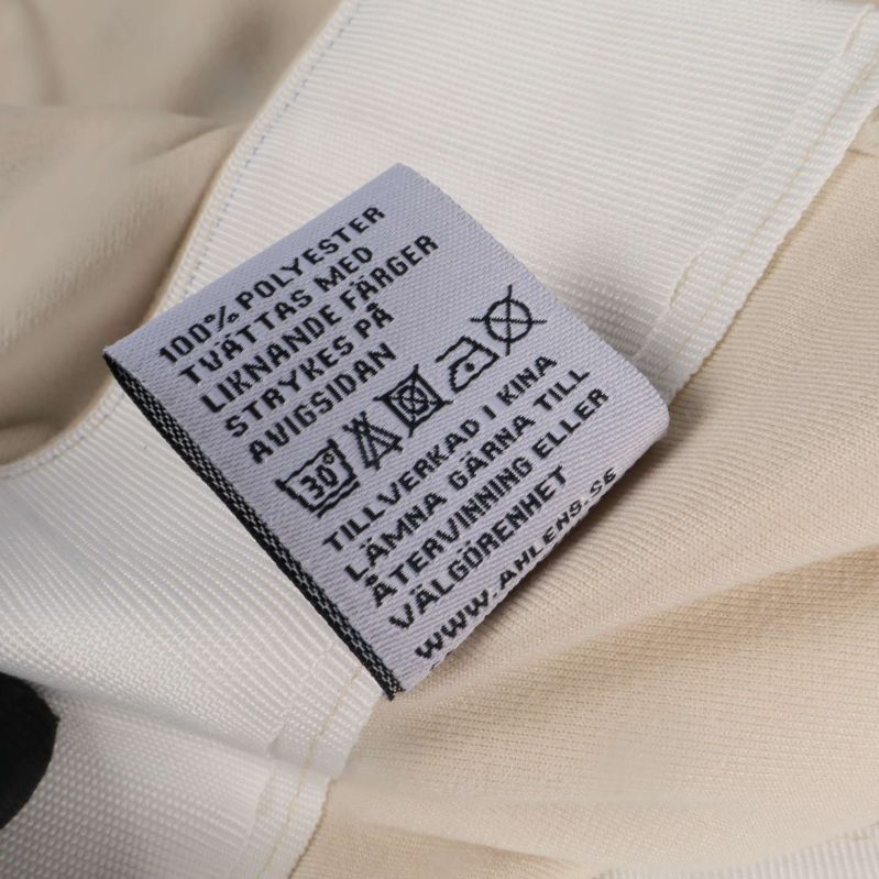 Materialetikett som visar 100% polyester och tvättråd