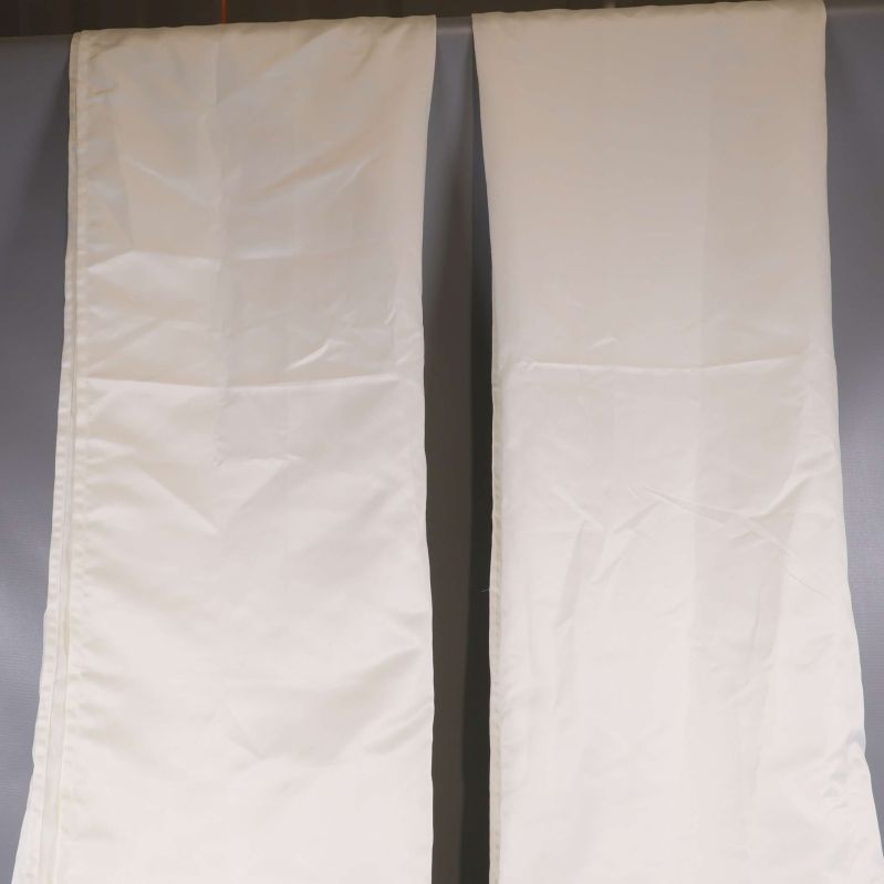 Två vita gardinlängder hänger mot grå bakgrund