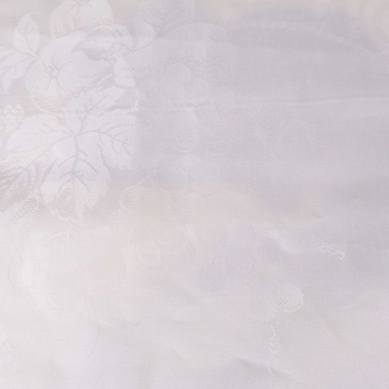 Närbild på tyg med blommigt mönster i vitt