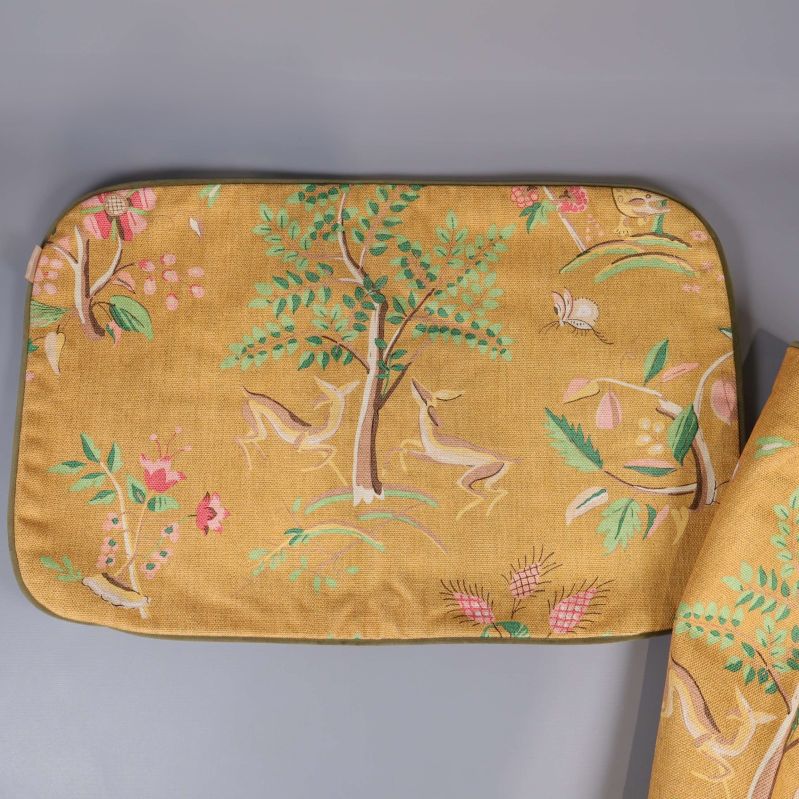 Närbild av kuddfodral med träd och rådjur på gult tyg